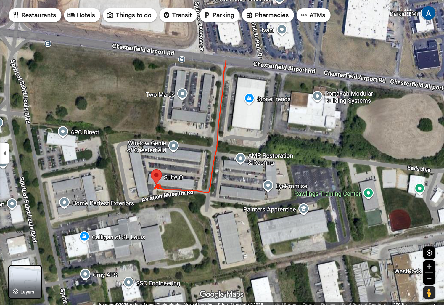 Aerial satellite map view of a commercial and industrial area with labeled buildings, roads, and navigation icons.