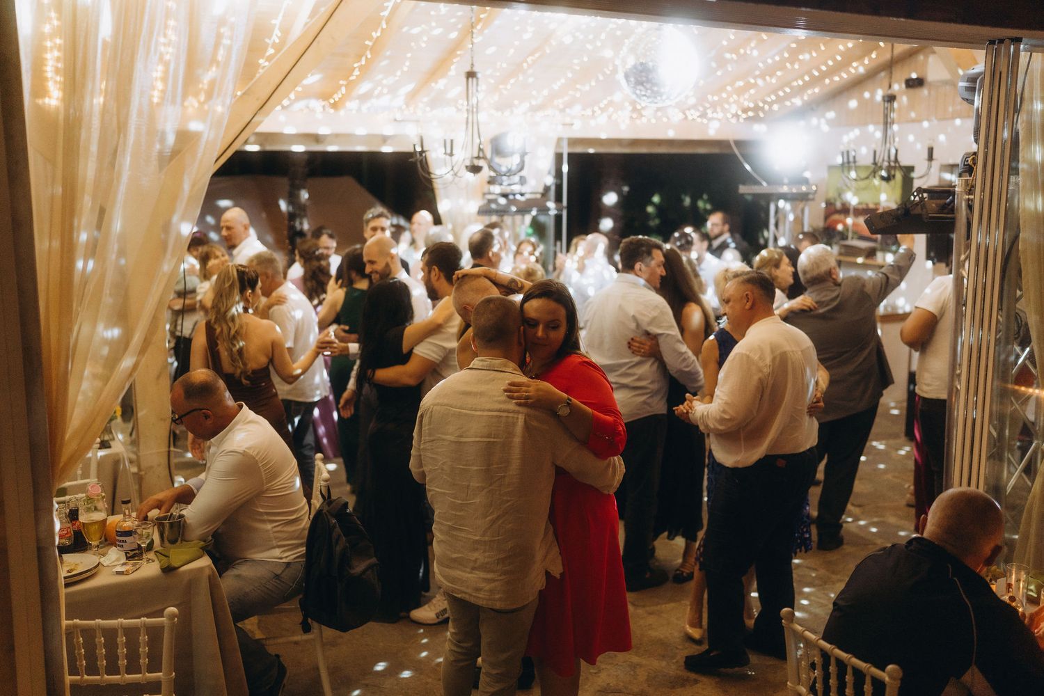 Guests dancing and celebrating under fairy lights at a romantic wedding reception venue.