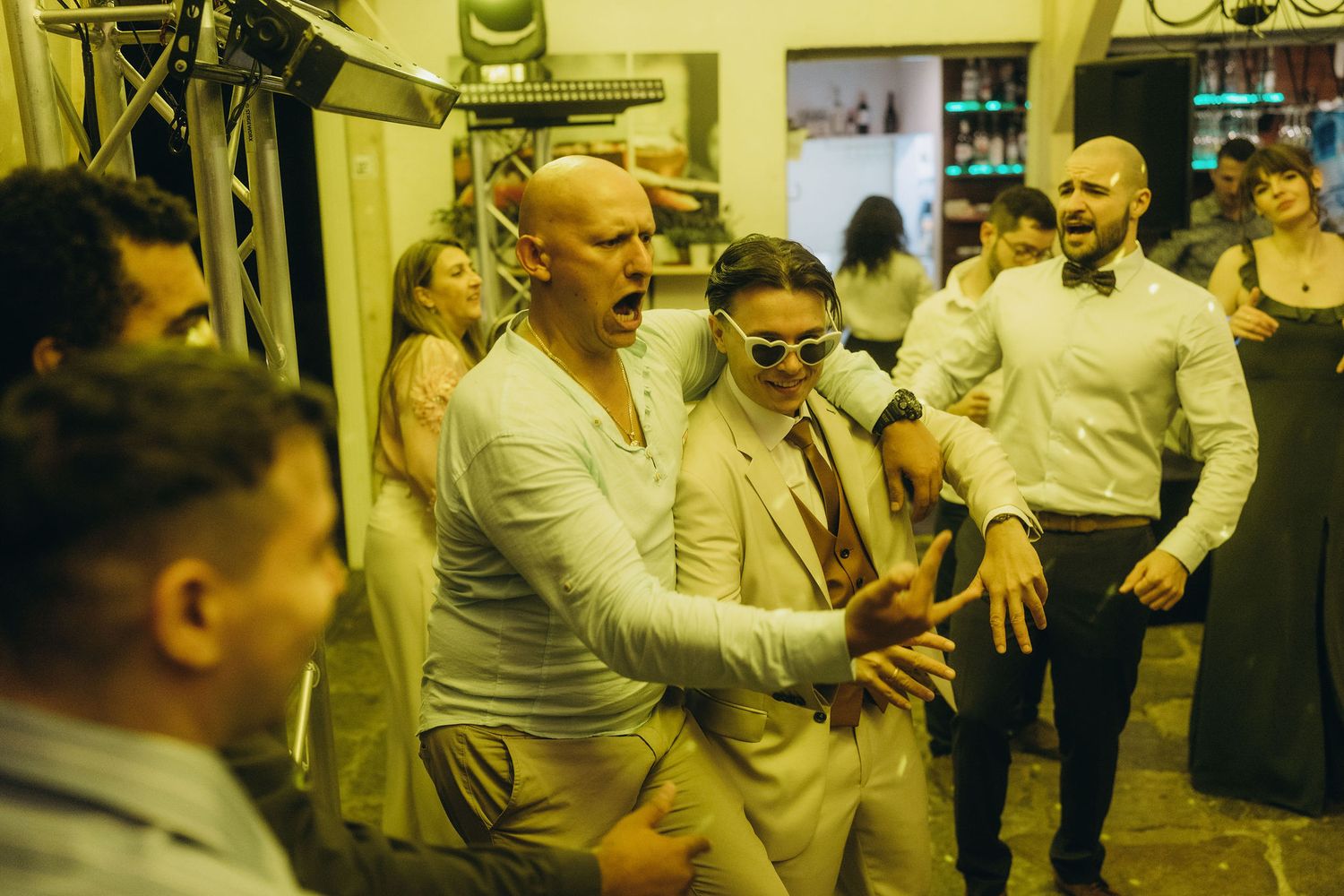 Guests dancing and celebrating energetically at an outdoor wedding reception party at night.