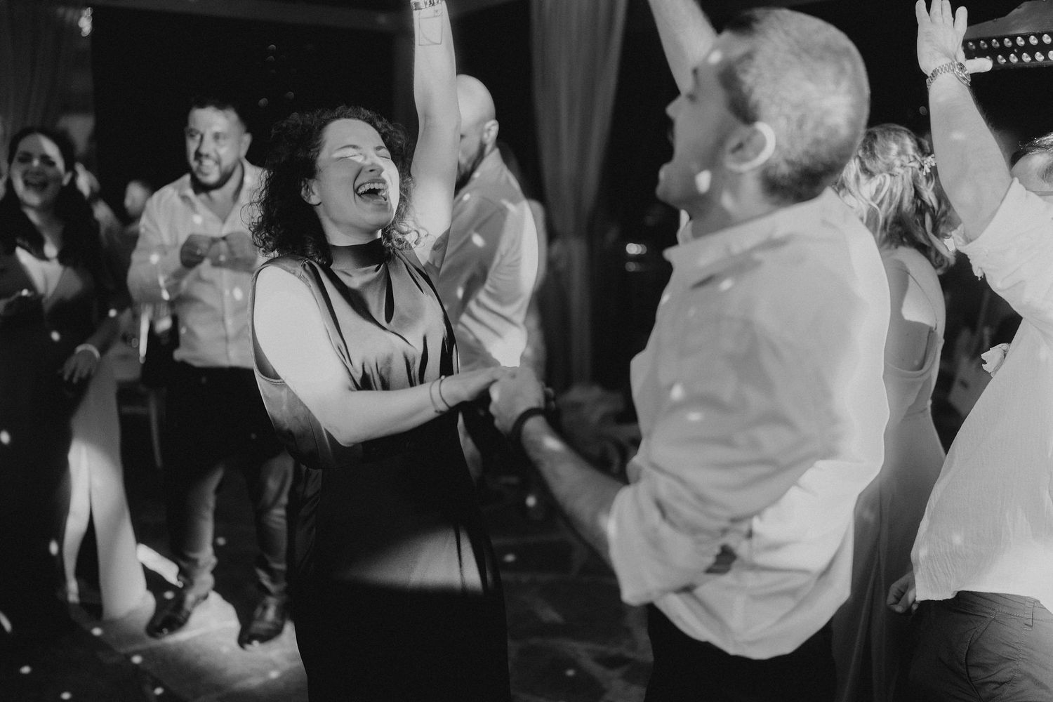 Joyful wedding guests dancing and celebrating with confetti at a lively reception party.