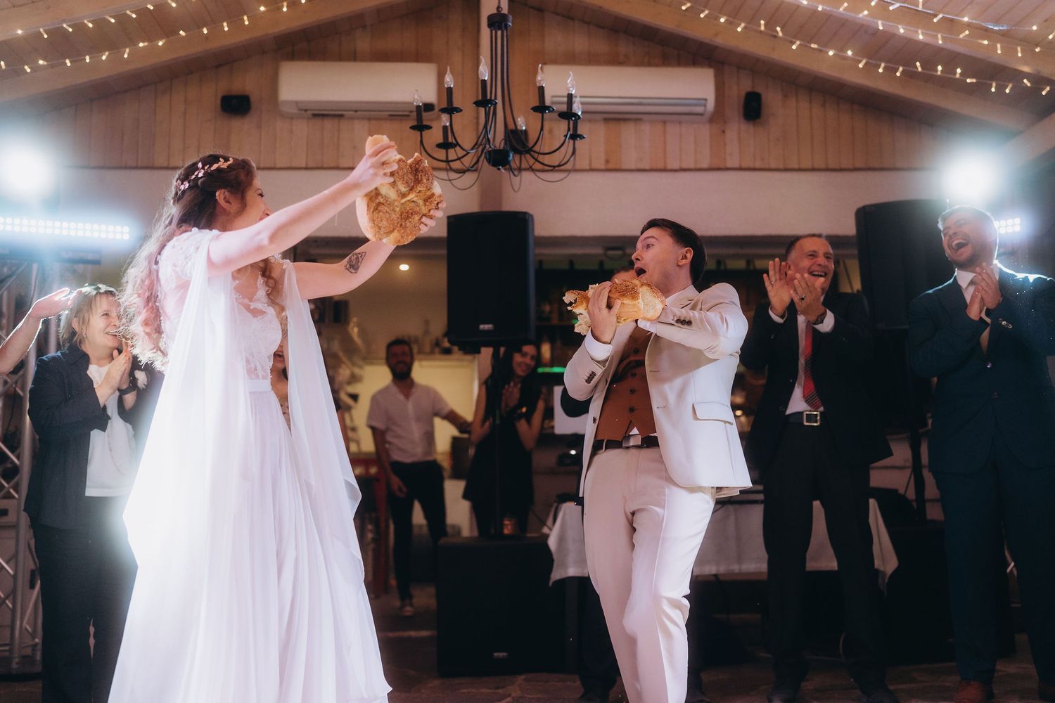 Bride and groom sharing a joyful first dance at their wedding reception with guests celebrating.