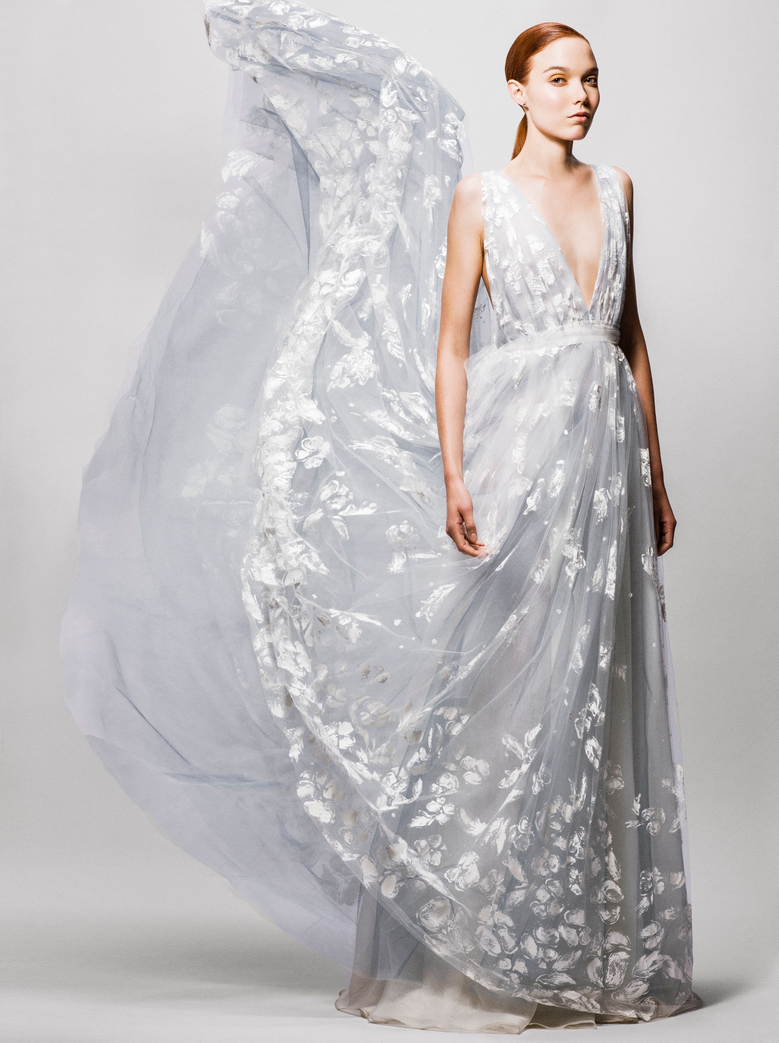 Elegant floral embroidered light blue-gray deep V-neck flowing gown with billowing fabric, perfect for a romantic bridal look.