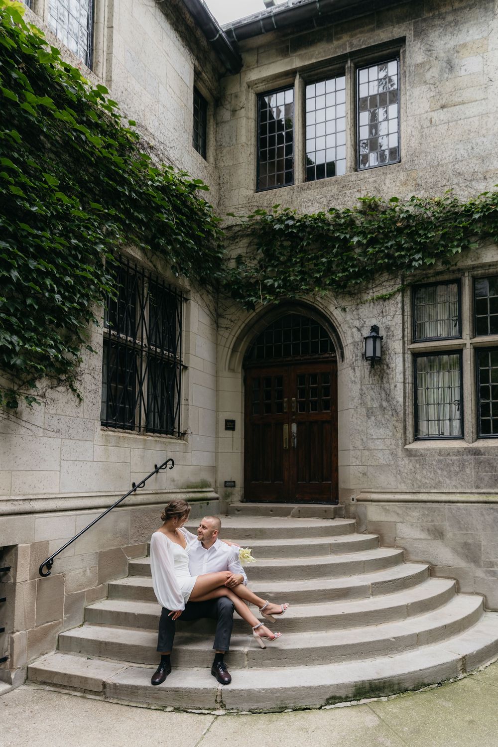 Couple sitting on stone steps of Fourth Presbyterian church in downtown Chicago during their engagement session