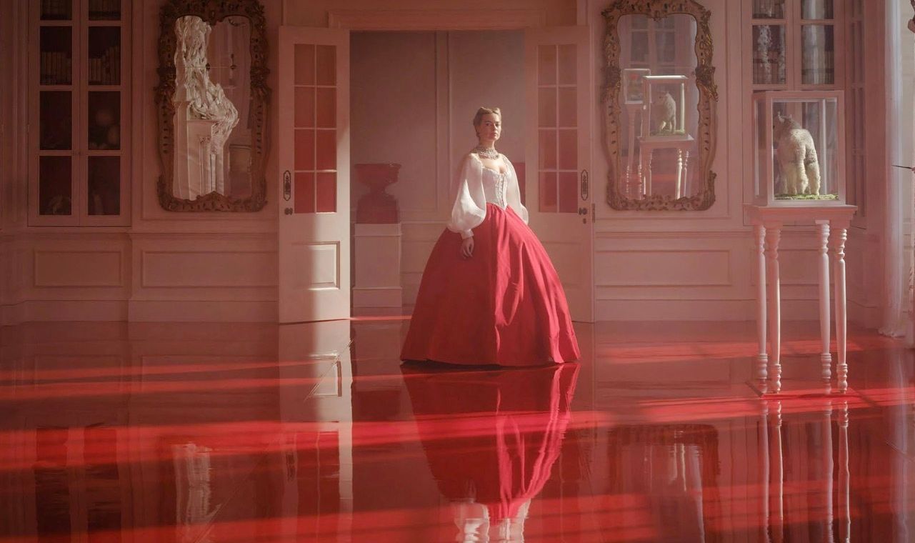 Woman in red ballgown stands in flooded ornate pink room with dramatic red water reflection.