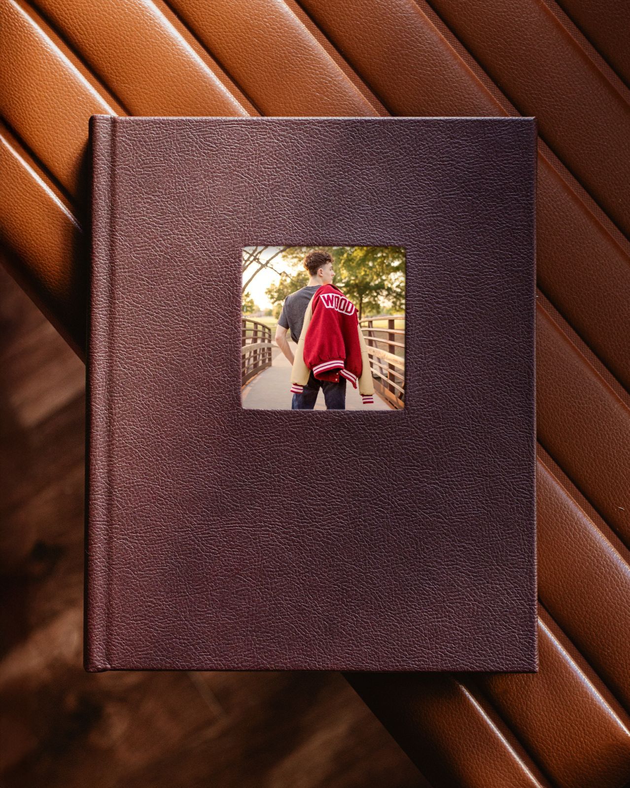 Dark brown leather photo album with a small window showcasing a young man in a red varsity jacket on a bridge in Keller, TX.