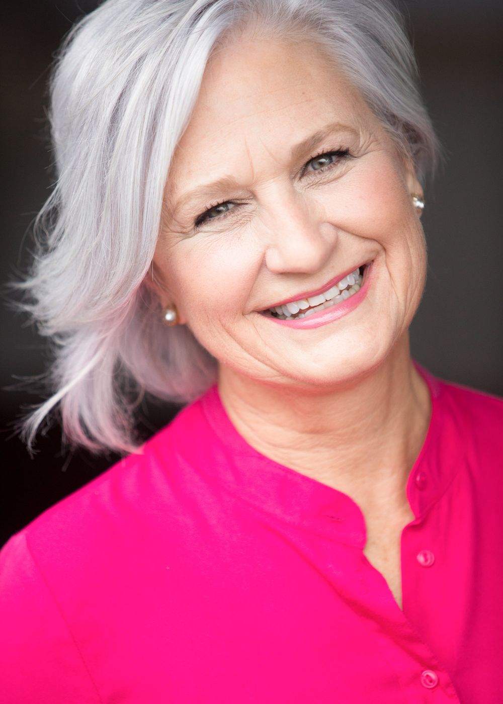 Cheerful portraits in bright pink top showing silver hair and natural expressions.