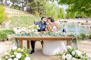 Wedding couple shares intimate moment at decorated outdoor table setting.
