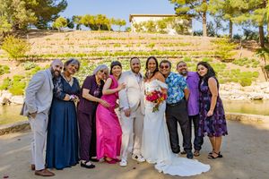 Wedding group in colorful attire poses outdoors against desert landscape.