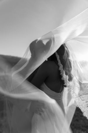 Artistic black and white close-up of flowing wedding veil in breeze.