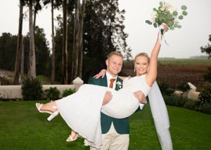 A celebratory moment captured outdoors with tall trees and a manicured lawn in the background.