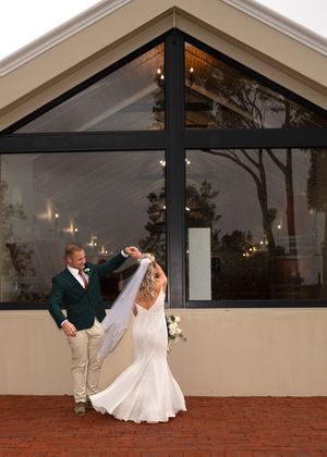 A couple dances together on a brick patio outside a glass-walled venue at dusk, creating a romantic silhouette.