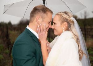 A tender moment between newlyweds embracing in formal wedding attire, with the bride in white and groom in emerald green.