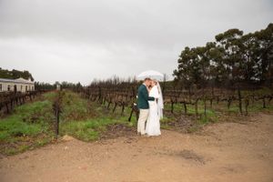 A romantic embrace in a vineyard with dormant winter vines under an overcast sky.