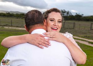 A joyful embrace captured during an outdoor wedding celebration with rolling hills in the background.