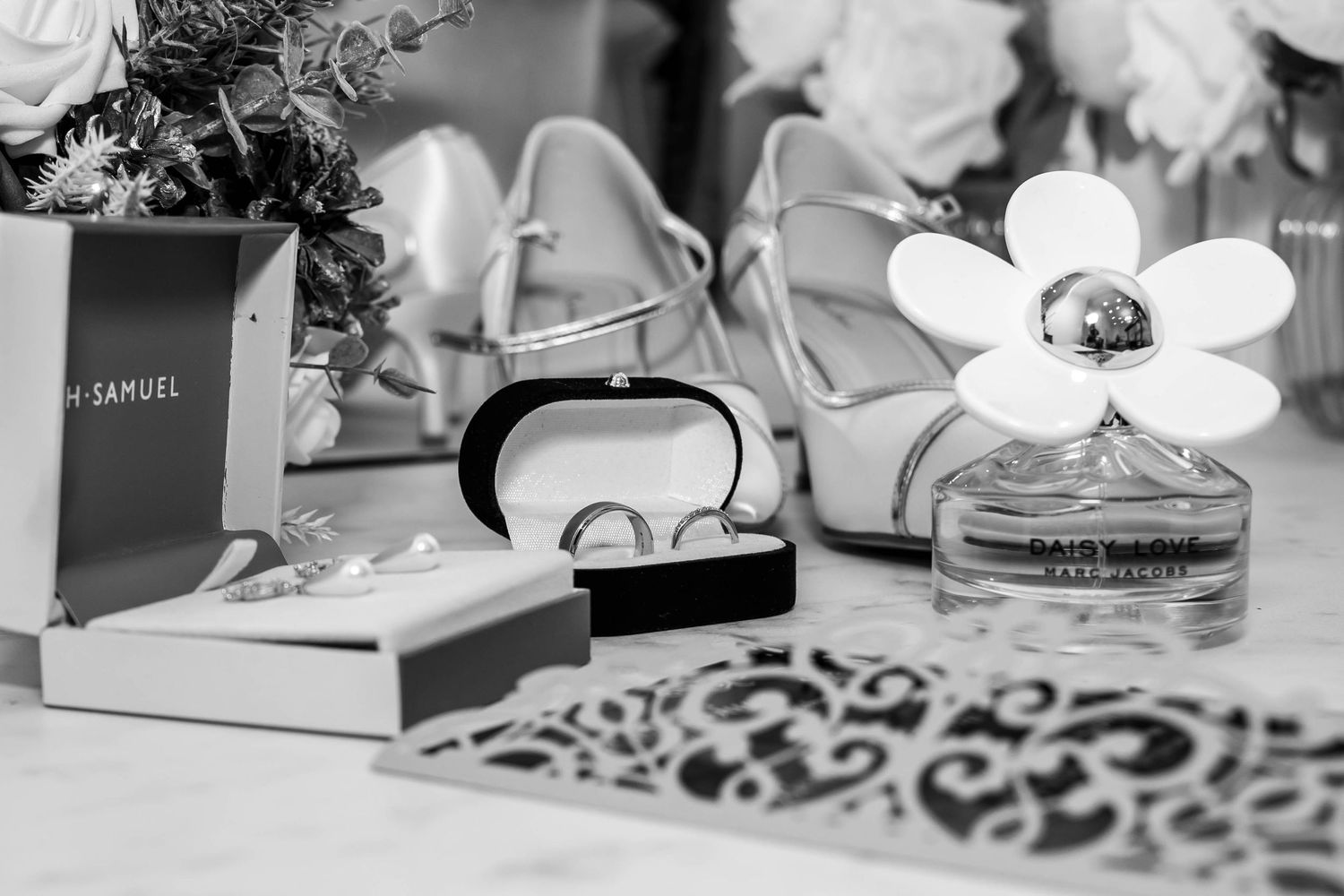Wedding details and accessories arranged on rustic wooden surface in black and white.
