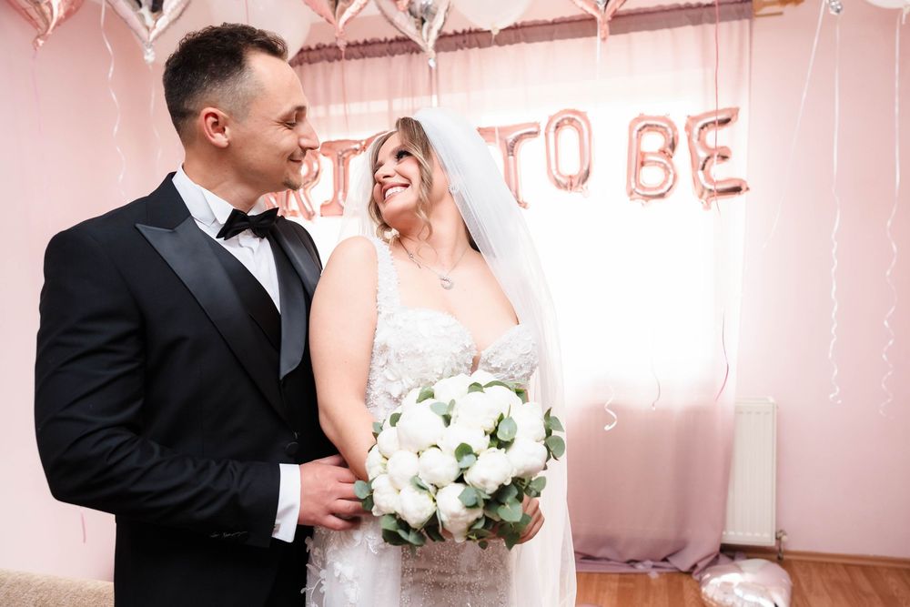 A couple shares a loving glance in front of rose gold 'BRIDE TO BE' balloon letters.