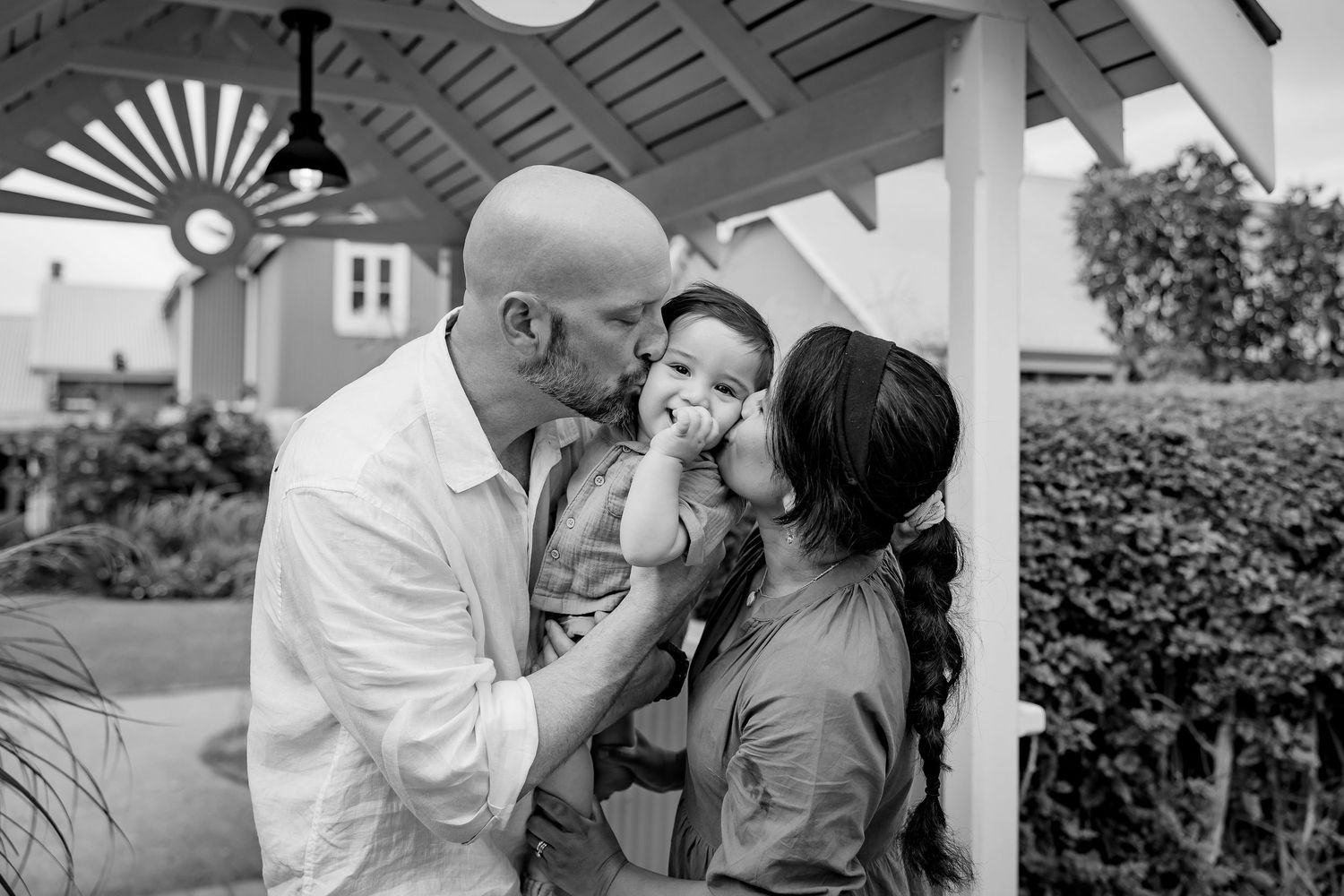 A joyful black and white candid photo of a parent and child sharing a loving embrace on sandy beach terrain.