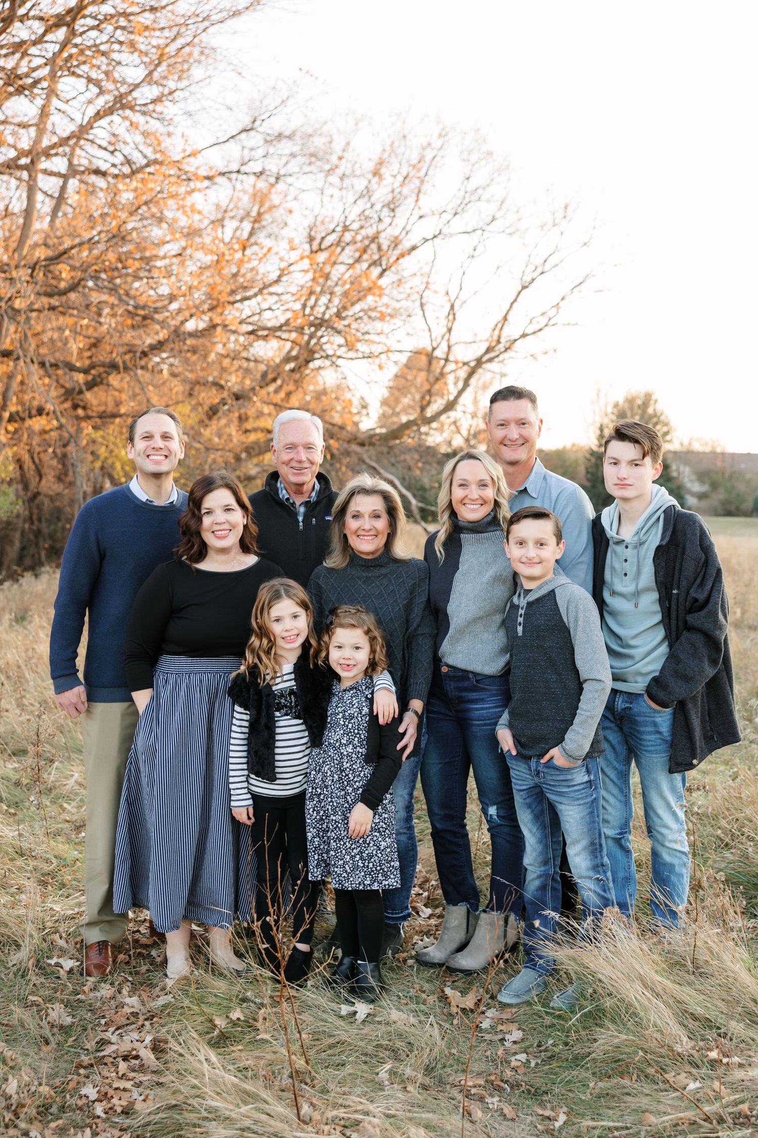 A family of six poses together outdoors in front of an evergreen tree during a winter photo session.
