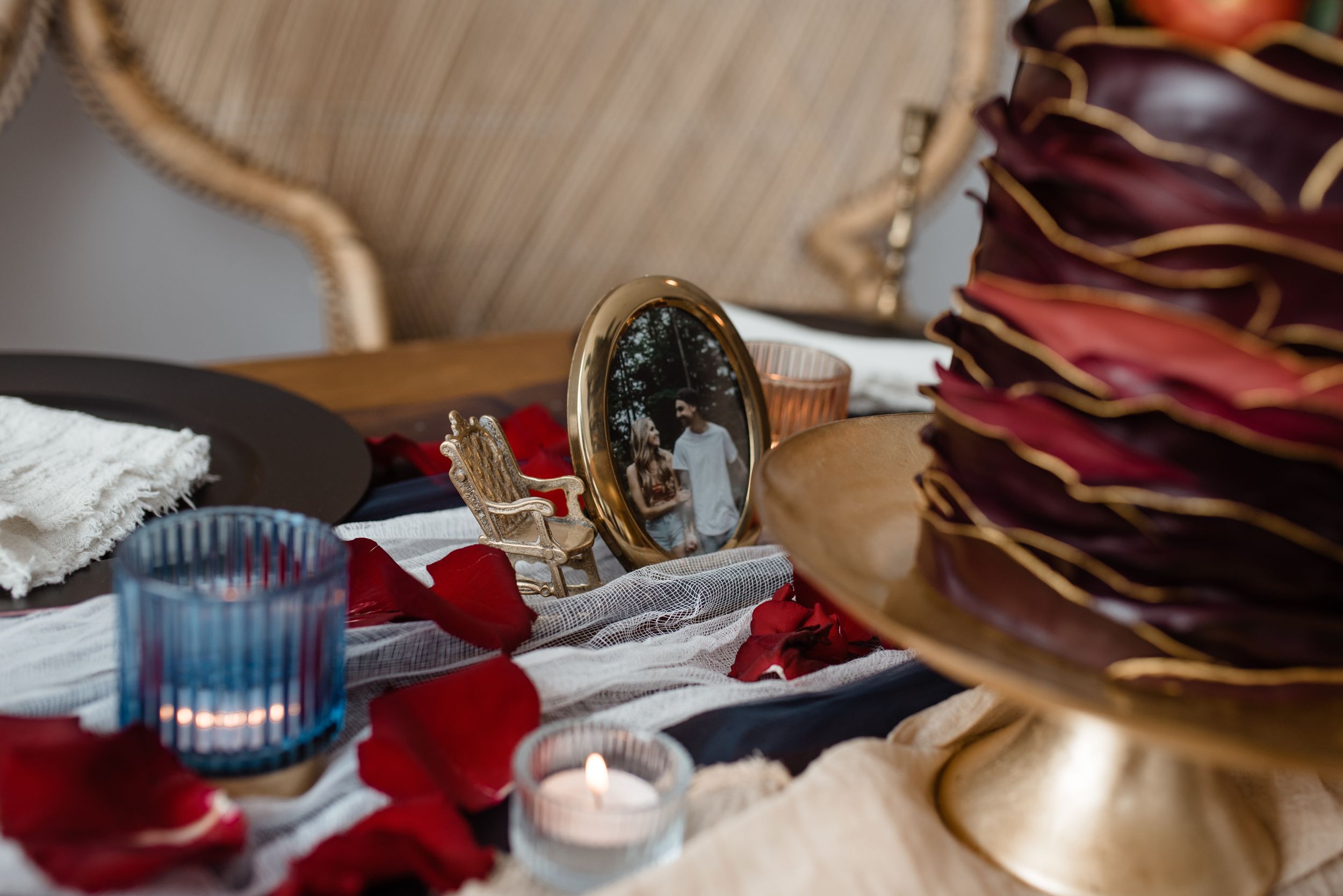 Wedding decor details featuring candles, red petals, and vintage decorative elements on a table.