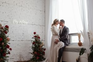 A romantic wedding scene with red roses against white brick walls and natural light.