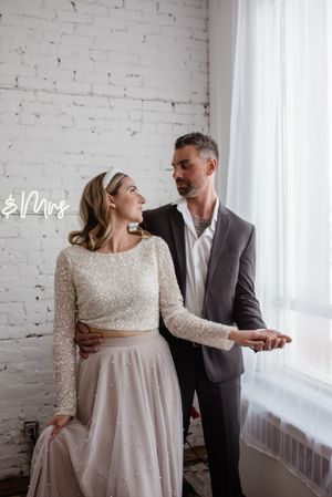 A romantic wedding portrait against white brick walls and window light.