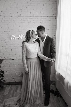 A black and white intimate wedding portrait against exposed brick and natural window light.