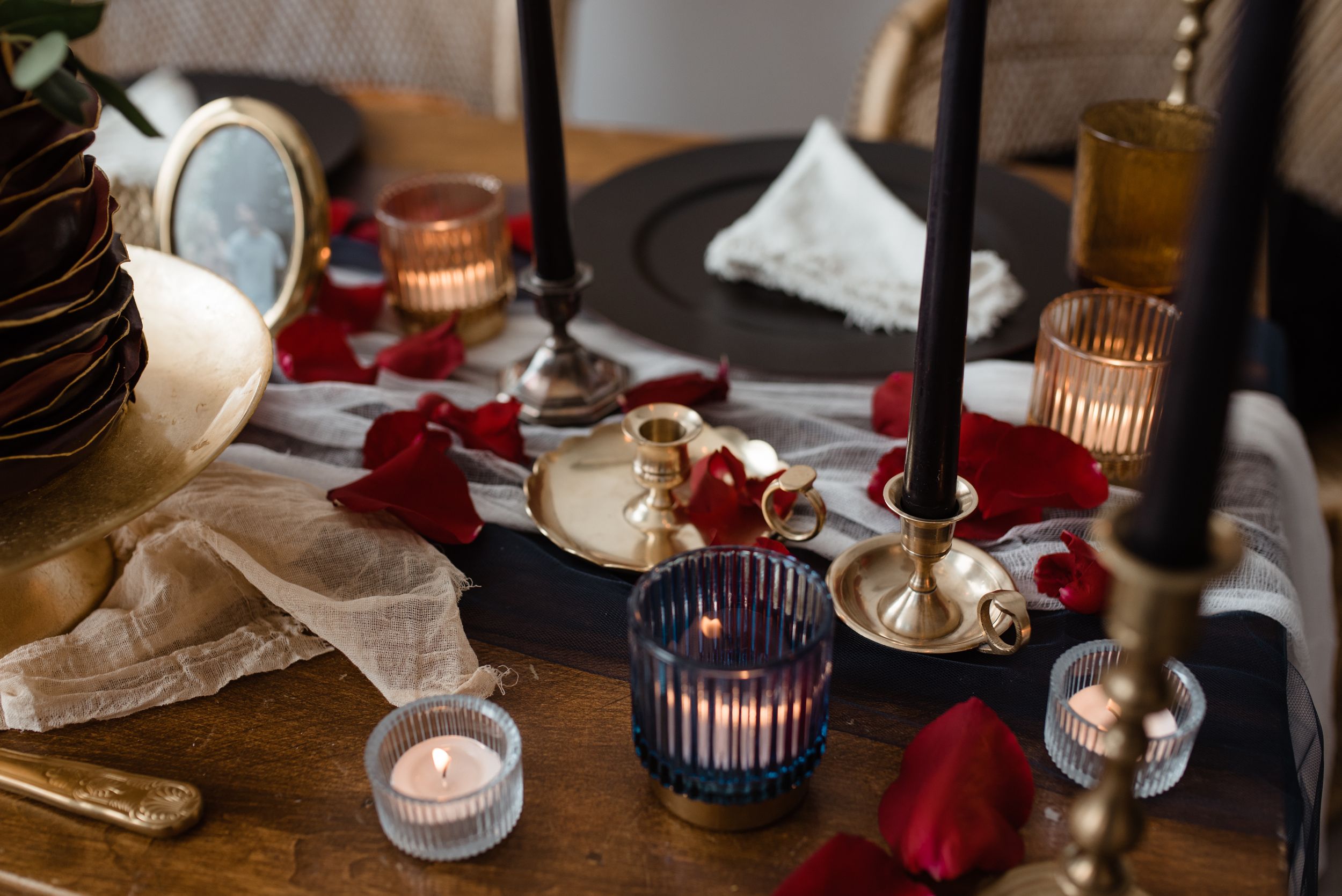 Elegant table setting with candleholders, red napkins and vintage decor for intimate wedding dinner.