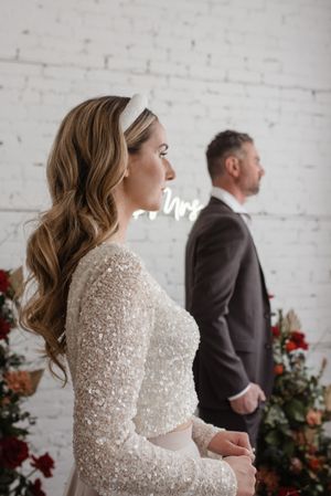 Side profile wedding portrait with sparkly dress details and floral arrangements.