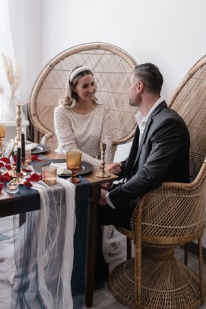 A couple shares an intimate moment at a table decorated with candles and beautiful floral arrangements.