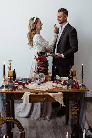 Couple sharing dessert moment at rustic table setting with candles and vintage decor.