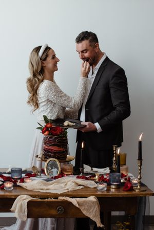 Elegant table setting with chocolate cake, candles and couple sharing a joyful moment.