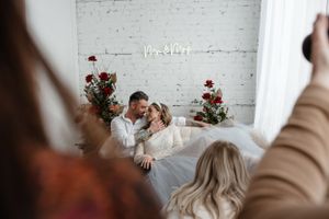 Behind-the-scenes wedding photo shoot with couple on vintage sofa.
