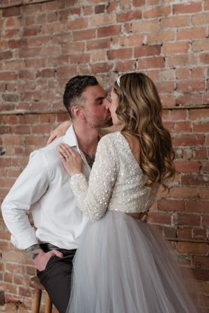 Intimate wedding portrait against exposed brick wall showing romantic embrace.