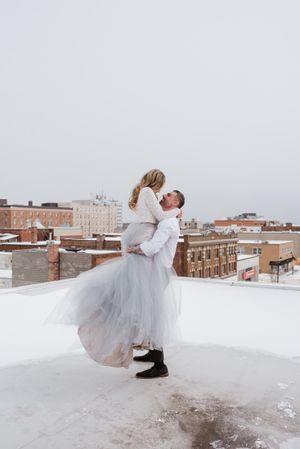 A celebratory lift on a snowy rooftop against an urban cityscape backdrop.