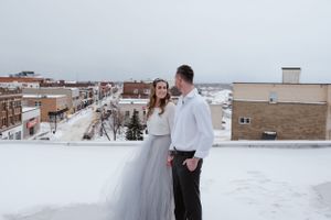 A winter rooftop wedding photo with snow-covered buildings in the background.