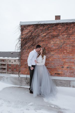 Winter wedding couple on a rooftop with brick wall and snow.