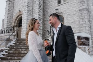 Winter wedding scene on stone steps of a historic church building.