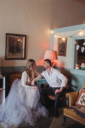 A couple shares a romantic moment on a vintage couch under warm lighting.