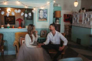 A romantic cafe scene with string lights and vintage decor as a couple converses at a table.