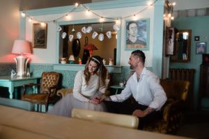 A vintage-style cafe setting with string lights and turquoise walls creates an intimate atmosphere.