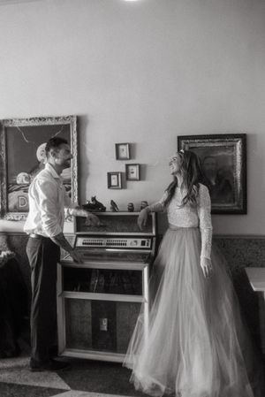 Black and white wedding photo by a piano showing a romantic moment.