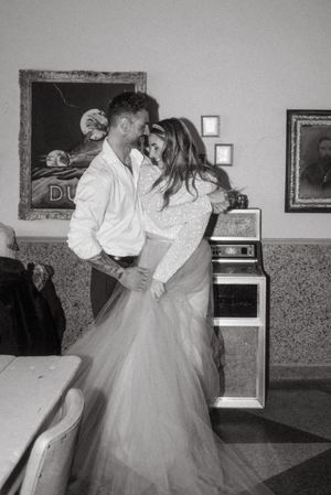 A romantic black and white photo of a bride and groom dancing in a vintage room.