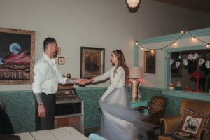 A playful dance moment in a vintage-style room with retro decor and string lights.