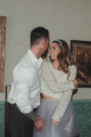 A romantic couple shares an intimate moment in evening wear with a sparkling crop top and flowing skirt.