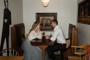 A couple shares an intimate moment at a vintage cafe table with artwork on the walls.