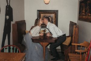 A romantic moment shared between a couple at a vintage cafe table with framed artwork.