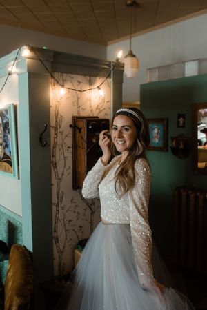 Bridal portrait in two-piece lace and tulle gown with headband under vintage lighting.