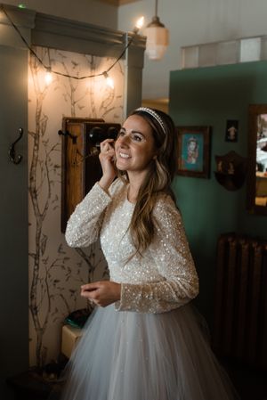 A sparkly long-sleeved wedding dress with tulle skirt captured in warm interior lighting.