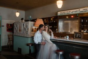 An intimate wedding moment at a vintage diner counter with turquoise walls.