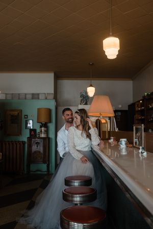 A couple shares an intimate moment at a retro diner counter with vintage lighting.